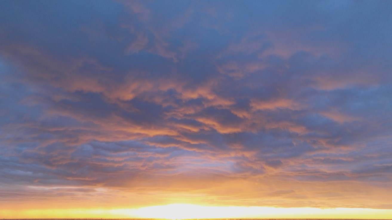 Mid-level clouds glow briefly, flowing at dawn with the rain