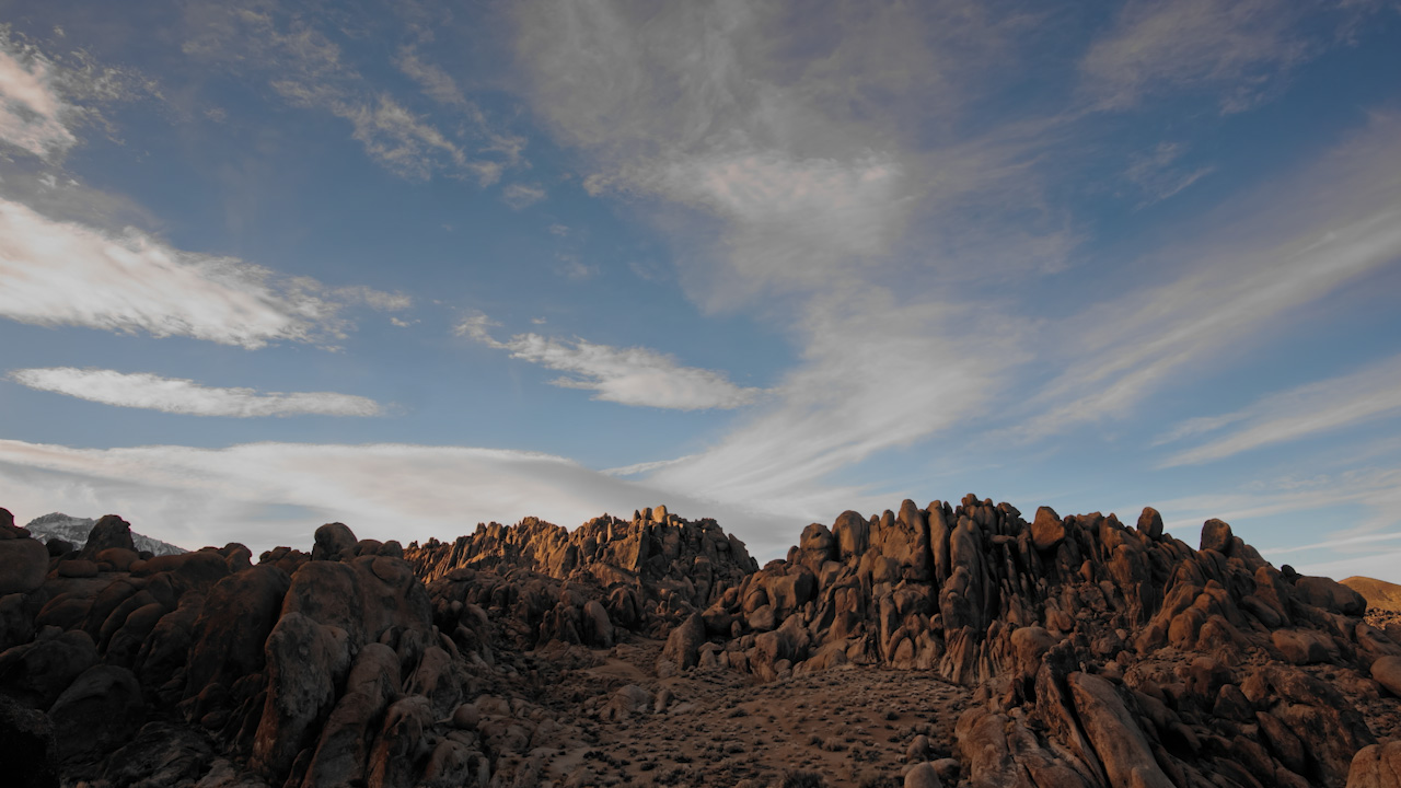 Dusk-to-night over rocky landscape into stars and blueish darkness overhead
