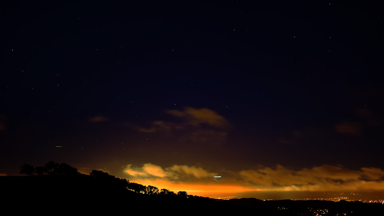 Silhouetted hill side by a city suburb at night