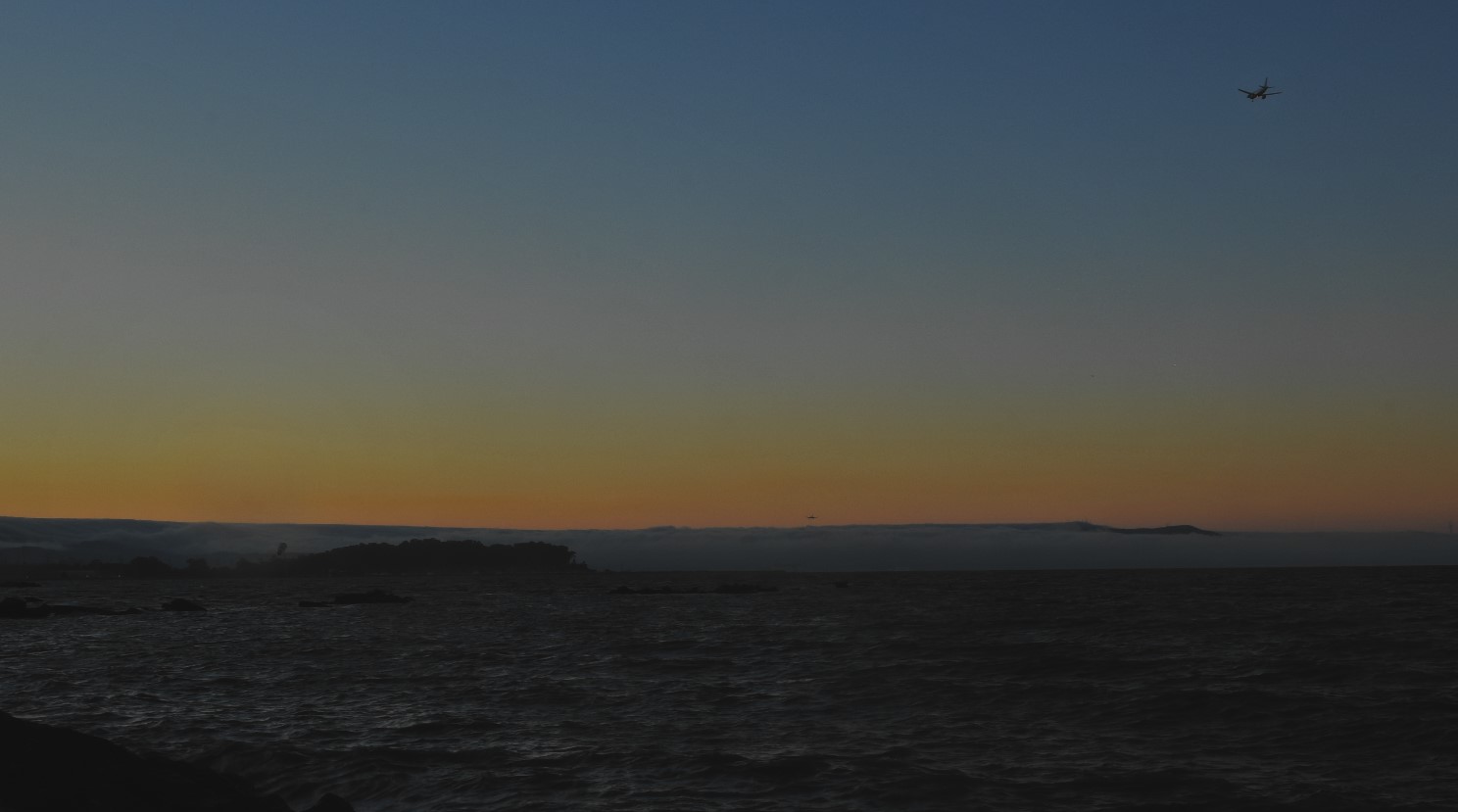 Thru dusk, airplanes land and para surfers persist on bay
